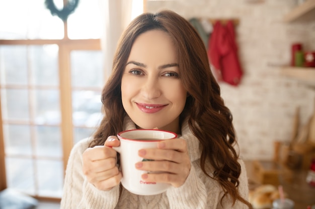 Mujer bonita feliz disfrutando de su té de la mañana