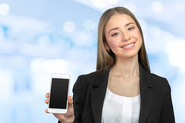 Mujer bonita feliz que muestra una pantalla en blanco del teléfono inteligente