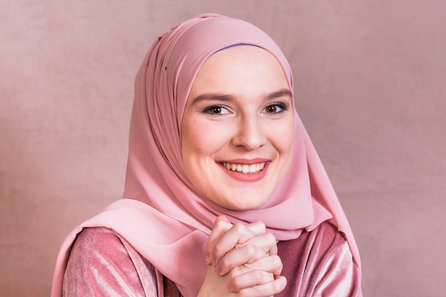 Foto mujer bonita feliz con sus manos juntas sobre fondo coloreado