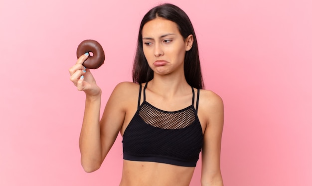 Mujer bonita fitness con una rosquilla y un tazón de desayuno