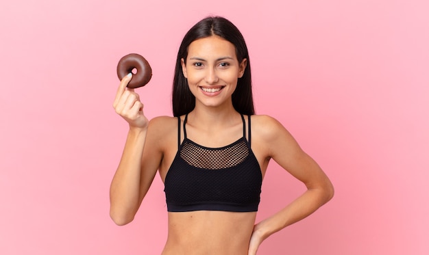 Mujer bonita fitness con una rosquilla y un tazón de desayuno