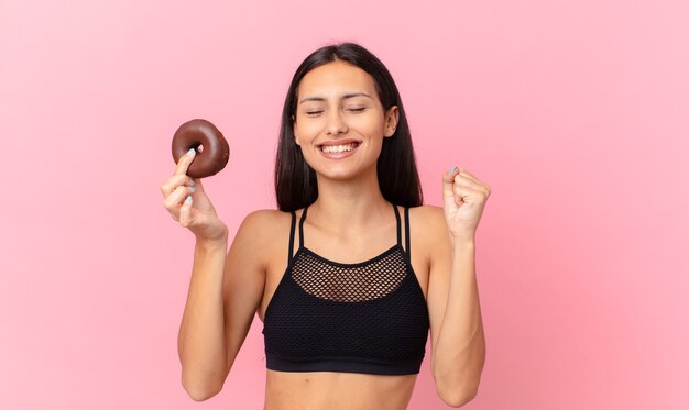 Mujer bonita fitness con una rosquilla y un tazón de desayuno