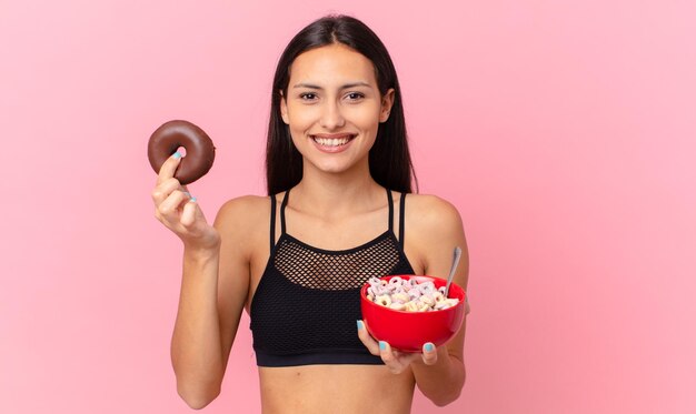 Mujer bonita fitness con una rosquilla y un tazón de desayuno