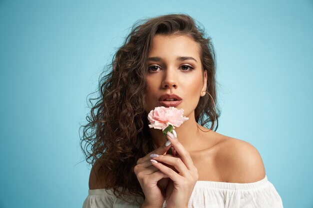 Mujer bonita con flor aislada en azul