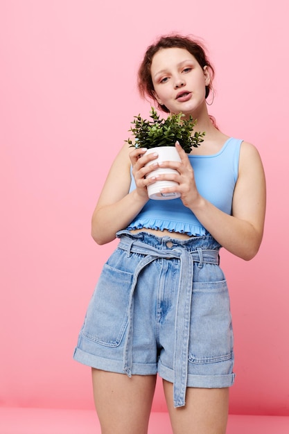 Mujer bonita flor en maceta posando planta fondo rosa inalterado