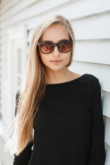 Mujer bonita en gafas de sol cerca de una pared de madera