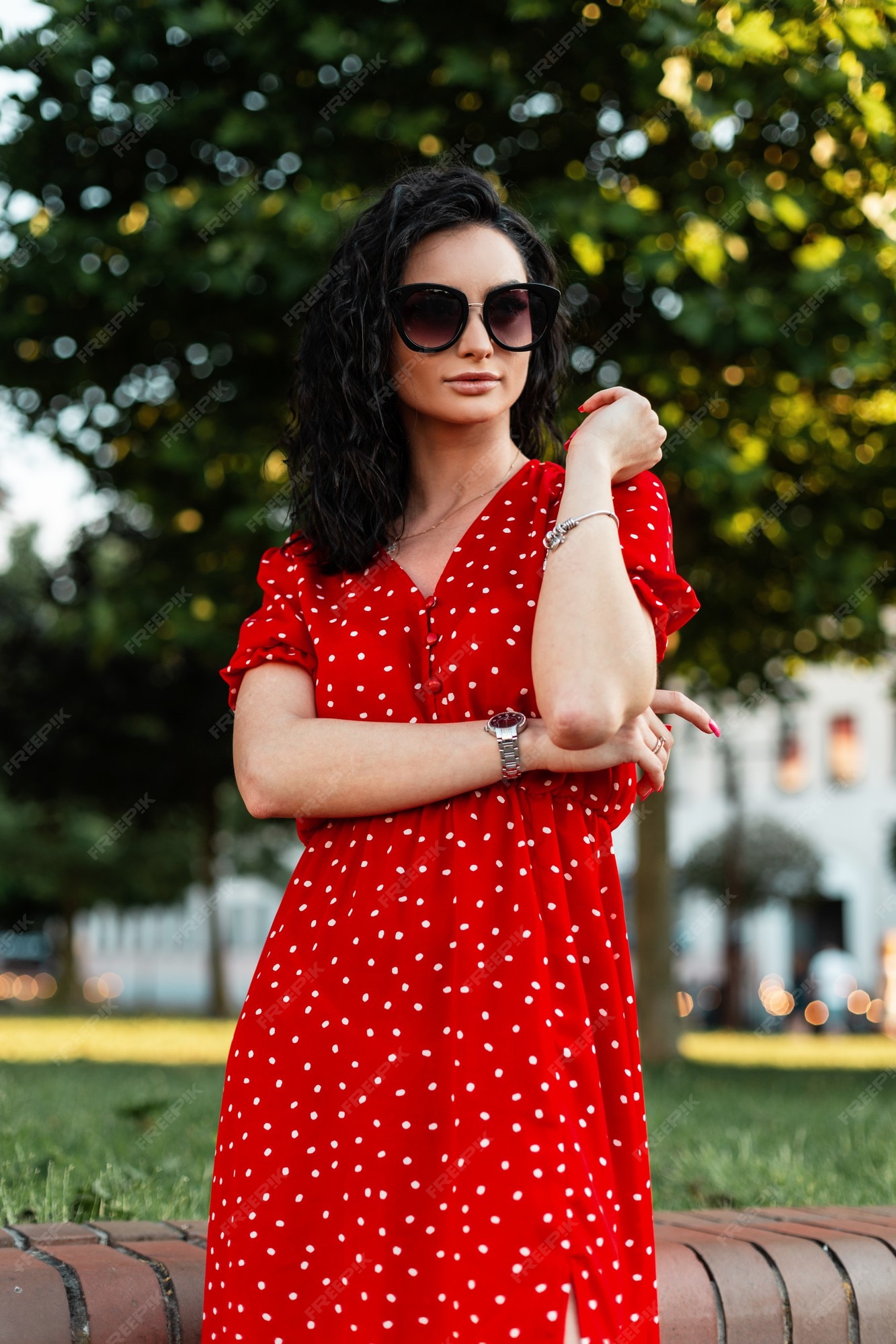 Mujer bonita con gafas de sol de en elegante rojo en el parque Foto Premium