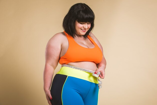 Mujer bonita de gran tamaño con ropa deportiva posando en el estudio