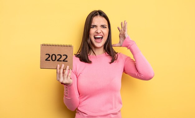 Mujer bonita gritando con las manos en el aire concepto de calendario 2022