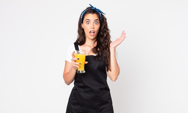 Mujer bonita gritando con las manos en el aire y sosteniendo un vaso de jugo de naranja