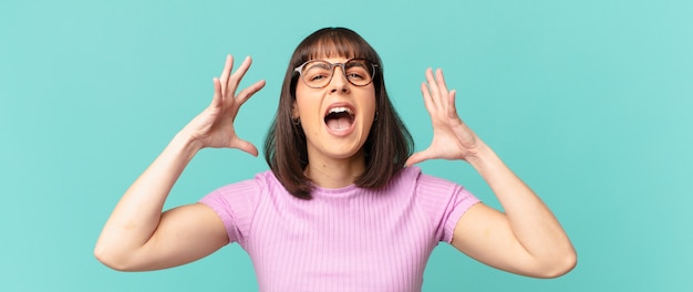 Foto mujer bonita gritando con las manos en alto, sintiéndose furiosa, frustrada, estresada y molesta