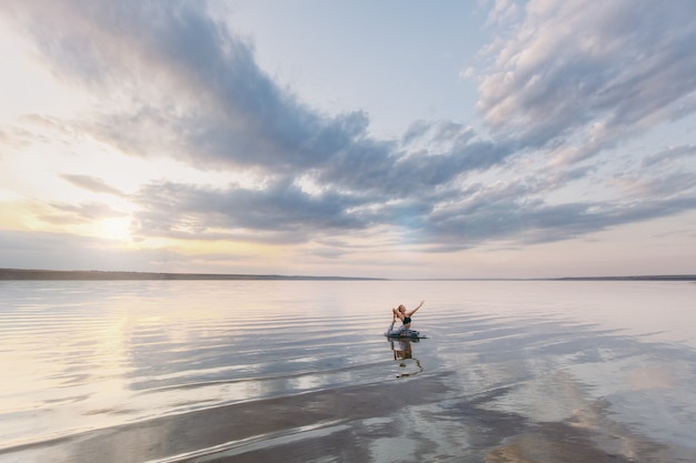 La mujer bonita haciendo yoga al atardecer al aire libre