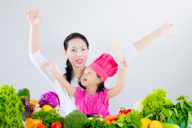 Mujer bonita con hija y verduras.