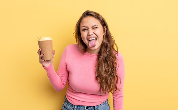 Mujer bonita hispana con actitud alegre y rebelde, bromeando y sacando la lengua. concepto de café para llevar