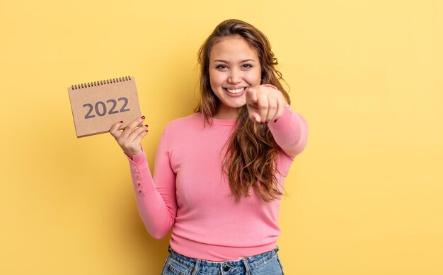 Mujer bonita hispana apuntando a la cámara escogiéndote. concepto de calendario