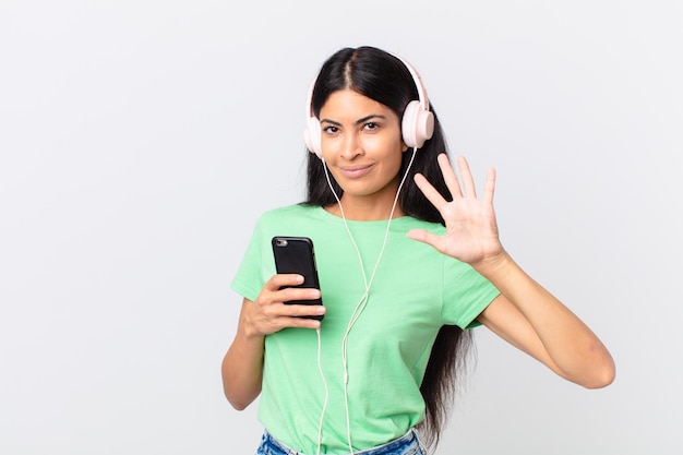 Mujer bonita hispana con auriculares y un teléfono inteligente