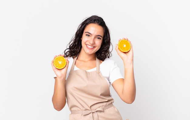 Mujer bonita hispana chef preparando un jugo de naranja