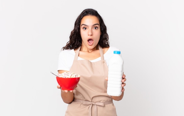 Mujer bonita hispana chef sosteniendo un tazón de desayuno con leche