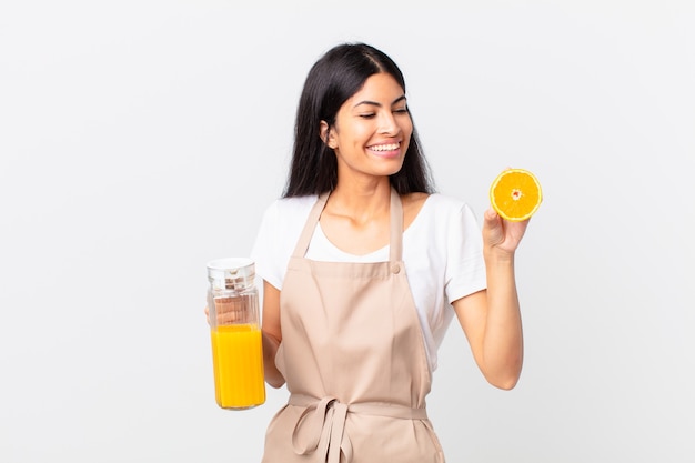 Mujer bonita hispana del cocinero. jugo de naranja y concepto de desayuno