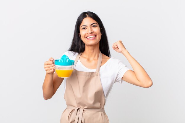 Mujer bonita hispana del cocinero. jugo de naranja y concepto de desayuno