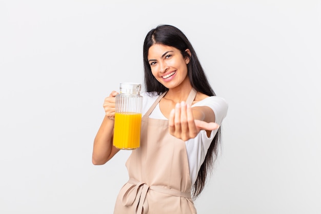 Mujer bonita hispana del cocinero. jugo de naranja y concepto de desayuno