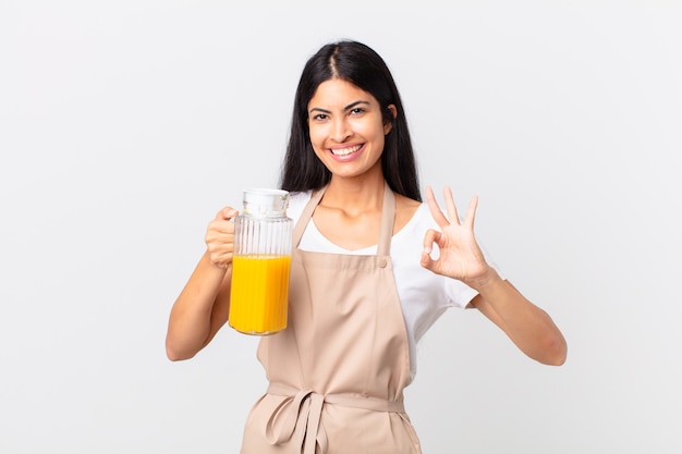 Mujer bonita hispana del cocinero. jugo de naranja y concepto de desayuno