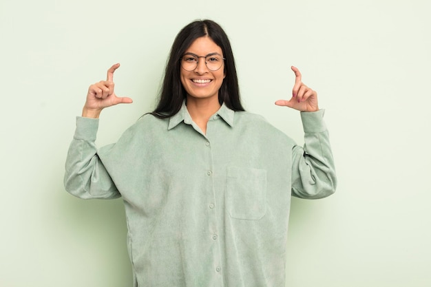 Mujer bonita hispana enmarcando o delineando su propia sonrisa con ambas manos luciendo un concepto de bienestar positivo y feliz