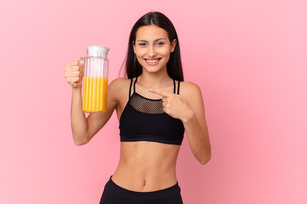 Mujer bonita hispana fitness con un jugo de naranja