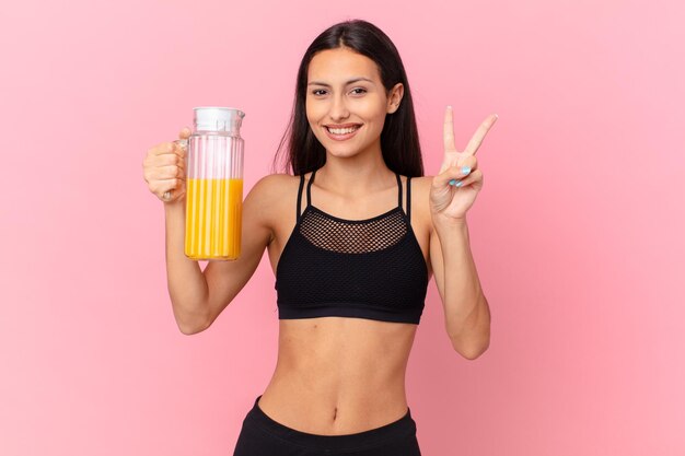 Mujer bonita hispana fitness con un jugo de naranja