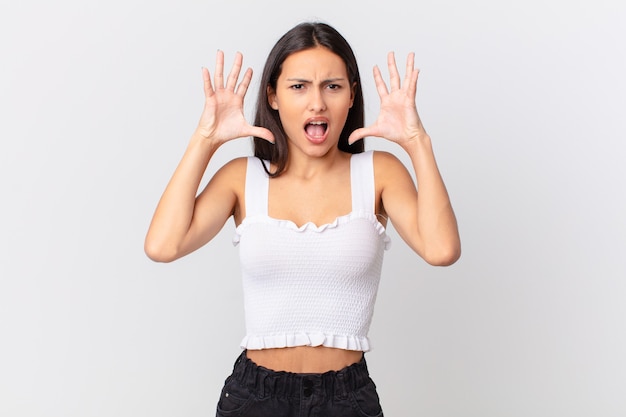 Mujer bonita hispana gritando con las manos en el aire