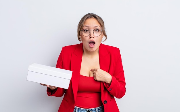 Mujer bonita hispana mirando consternado y sorprendido con la boca abierta, apuntando a sí mismo. concepto de producto de paquete