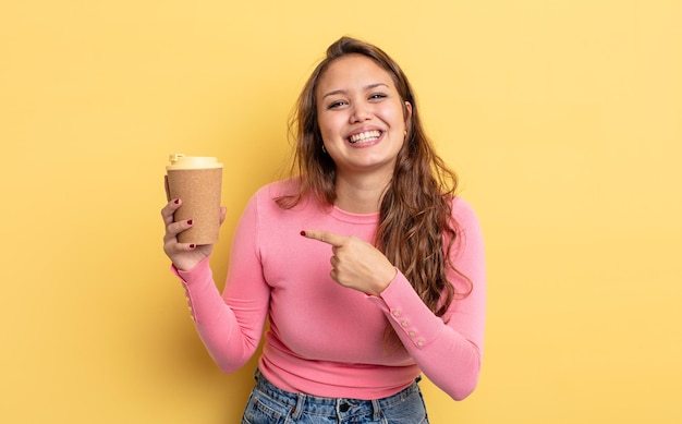 Mujer bonita hispana mirando emocionado y sorprendido apuntando hacia un lado. concepto de café para llevar