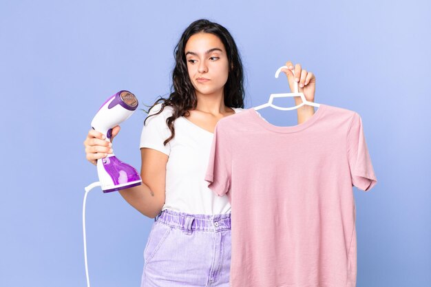 Foto mujer bonita hispana con una plancha de vapor y ropa.