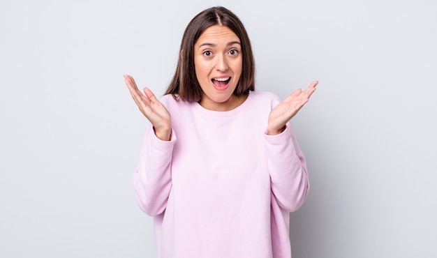 Mujer bonita hispana que parece feliz y emocionada, sorprendida con una sorpresa inesperada con ambas manos abiertas junto a la cara