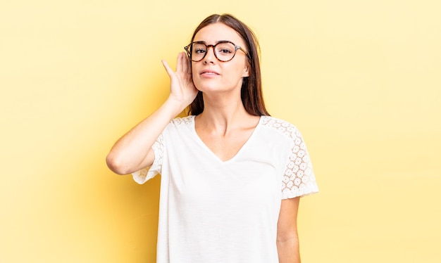 Mujer bonita hispana que parece seria y curiosa, escuchando, tratando de escuchar una conversación secreta o chismes, escuchando a escondidas