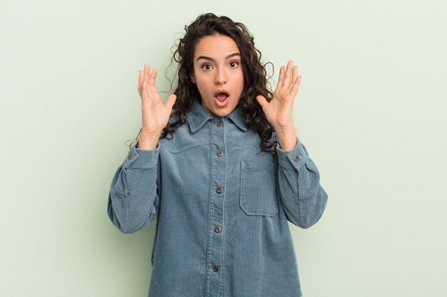 mujer bonita hispana que parece sorprendida y asombrada, con la boca abierta de sorpresa al darse cuenta de algo increíble