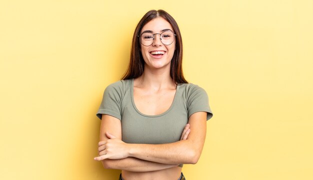 Mujer bonita hispana que parece un triunfador feliz, orgulloso y satisfecho sonriendo con los brazos cruzados