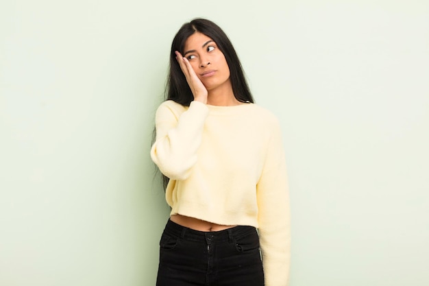 Mujer bonita hispana que se siente aburrida frustrada y con sueño después de una tarea aburrida y tediosa sosteniendo la cara con la mano