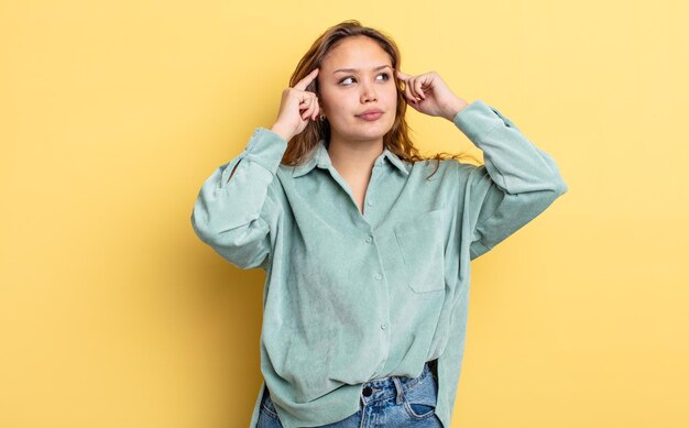 Mujer bonita hispana que se siente confundida o dudando de concentrarse en una idea pensando mucho buscando copiar espacio en el costado