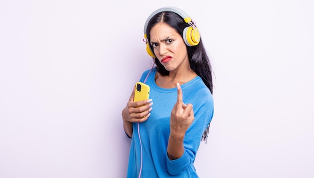 Mujer bonita hispana que se siente enojada, molesta, rebelde y agresiva. concepto de teléfono inteligente y auriculares