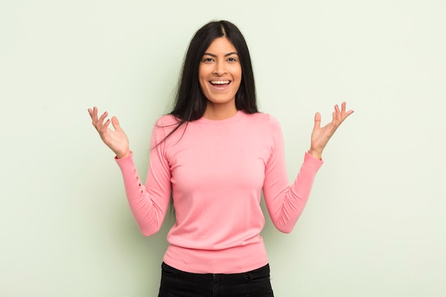 Mujer bonita hispana que se siente feliz emocionada sorprendida o conmocionada sonriendo y asombrada por algo increíble