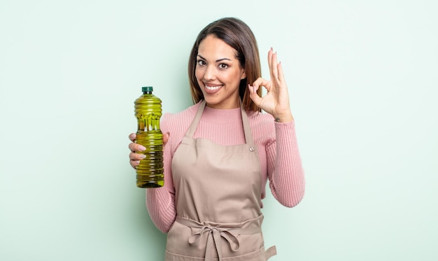 Mujer bonita hispana que se siente feliz, mostrando aprobación con gesto bien. concepto de aceite de oliva