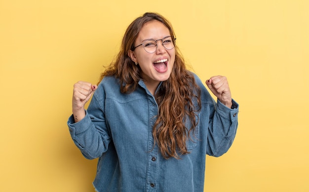 Mujer bonita hispana que se siente feliz, positiva y exitosa, celebrando la victoria, los logros o la buena suerte