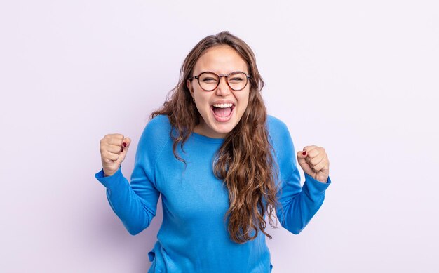 Mujer bonita hispana que se siente feliz, sorprendida y orgullosa, gritando y celebrando el éxito con una gran sonrisa