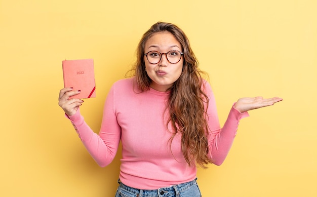 Mujer bonita hispana que se siente perpleja, confundida y dudando. concepto de agenda