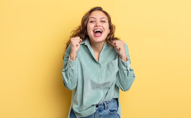 Mujer bonita hispana que se siente sorprendida, emocionada y feliz riendo y celebrando el éxito diciendo wow