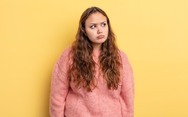 Mujer bonita hispana que se siente triste, molesta o enojada y mira hacia un lado con una actitud negativa, frunciendo el ceño en desacuerdo