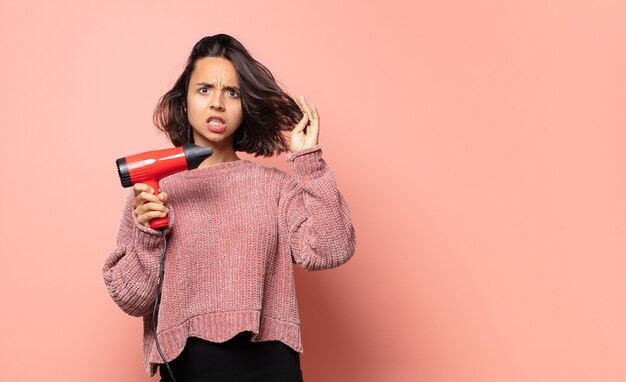 Mujer bonita hispana con secador de pelo