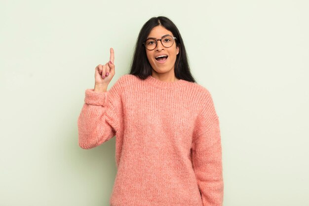 Mujer bonita hispana sintiéndose como un genio feliz y emocionado después de darse cuenta de una idea levantando alegremente el dedo eureka