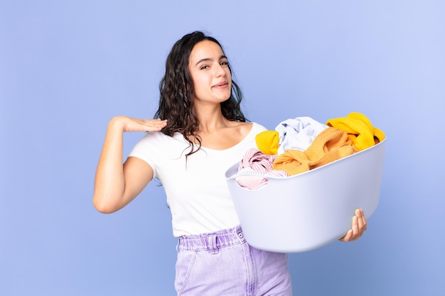 Mujer bonita hispana sintiéndose estresada, ansiosa, cansada y frustrada y sosteniendo una canasta de lavar ropa